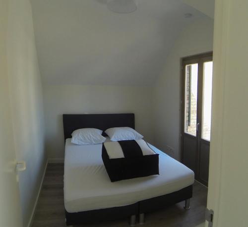 德帕内ons kotje的一间卧室配有一张带白色床单的床和一扇窗户。