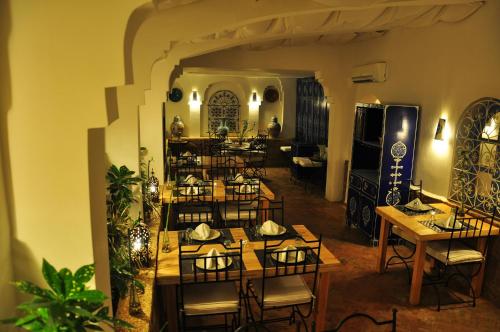 艾西拉Hotel Al Alba Hammam & Restaurant的一间在房间内配有桌椅的餐厅