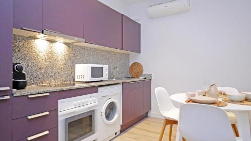 坎布里尔斯Cambrils 4的厨房配有紫色橱柜和带微波炉的桌子