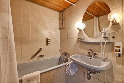 韦因斯塔特拉姆酒店的一间带水槽、浴缸和镜子的浴室