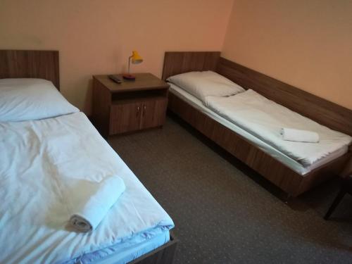 新苏尔Hotel Polonia的客房设有两张床和一张带台灯的桌子。