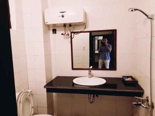 岑山Khách sạn Hồ Gươm的照着浴室镜子的人