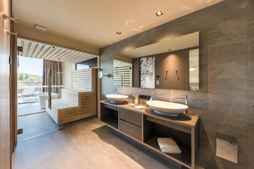 阿皮亚诺苏拉斯特拉达Weinegg Wellviva Resort的带大镜子的浴室内的2个盥洗盆