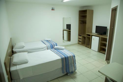 马卡帕玛卡帕巴酒店的一间卧室配有两张白色的床和电视