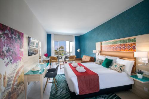 帕福斯Leonardo Cypria Bay的酒店客房带一张床、一张桌子和椅子