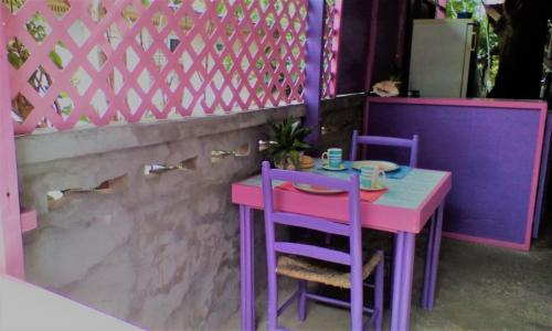 格罗斯岛特别地方旅馆的粉红色和紫色的桌子和两把紫色的椅子