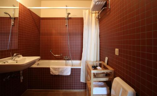 阿尔斯霍特赫多根莫伦酒店的红色瓷砖浴室设有浴缸和水槽