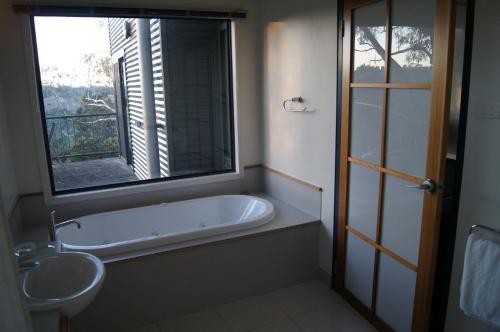 GrindelwaldRiver Vineyard Retreat的带浴缸、水槽和窗户的浴室