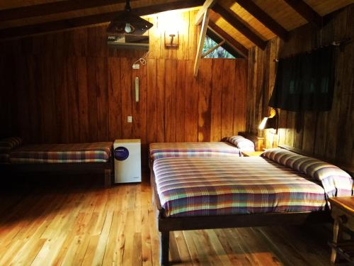 阿里斯托布罗德瓦里Posada Camboatá的配有木墙和木地板的客房中的两张床