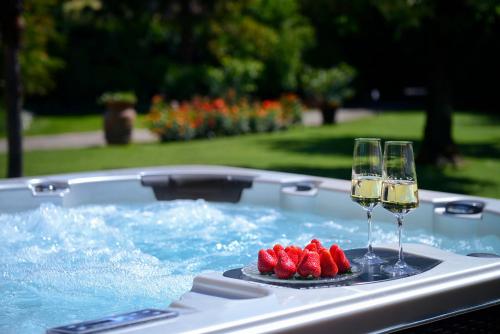 特拉诺瓦-布拉乔利尼Villa Le Facezie B&B的热水浴池内提供2杯葡萄酒和草莓