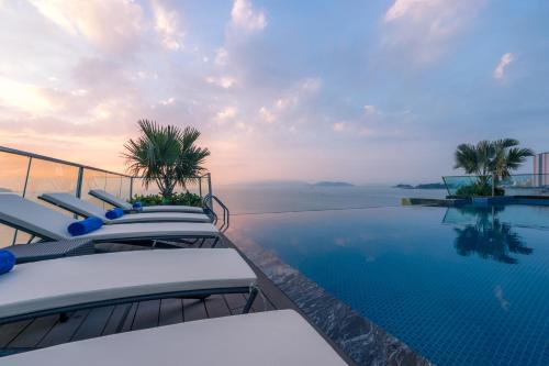 芽庄Boton Blue Hotel & Spa的一个带椅子的游泳池,背景是大海