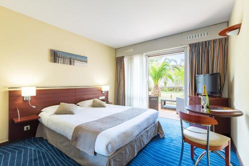 圣拉斐尔Hotel Brise de Mer - Piscine intérieure & extérieure的酒店客房设有床、桌子和窗户。