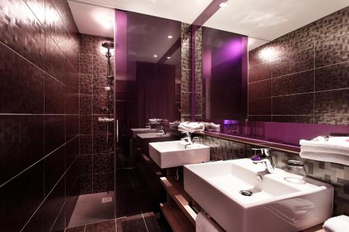 图卢兹斯特兹酒店的浴室设有3个水槽和1面带紫色照明的镜子