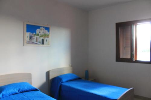 梅伦杜尼奥Residenza Santoro的一间卧室设有两张带蓝色床单的床和窗户。