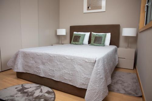 布拉加Design Flat in Braga - by TonsdeVerde的卧室配有带绿色枕头的大型白色床