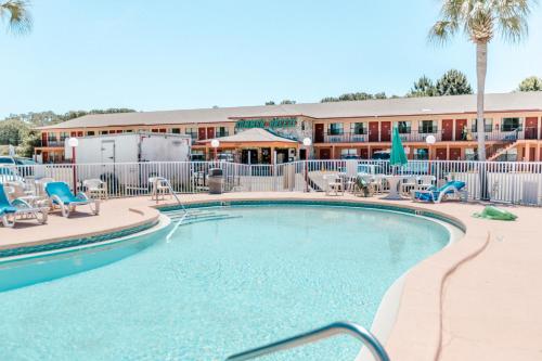 巴拿马城海滩夏日微风汽车旅馆的一个带椅子的游泳池和一个位于酒店后面的酒店