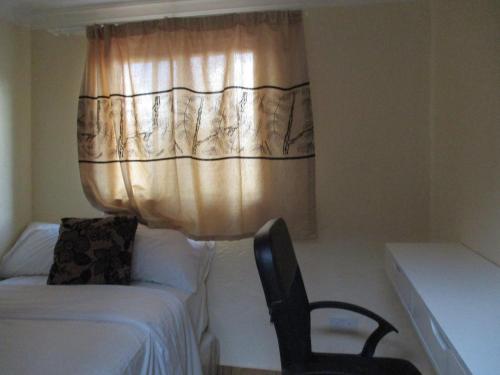 利隆圭Avon Apartments的一间卧室配有床、椅子和窗帘