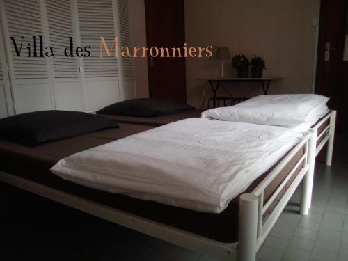 米朗德Villa Des Marronniers的卧室内的两张床,配有白色床单和枕头