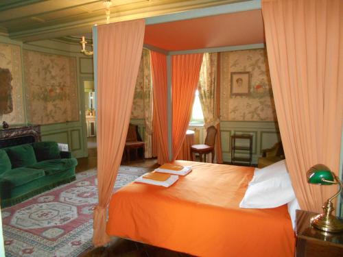 Parigny埃利拉城堡酒店的一间卧室配有橙色天蓬床和沙发
