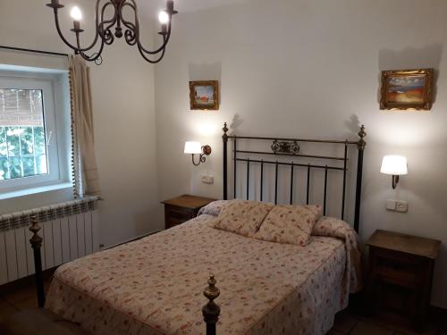 Casas del MonteLa Casa de la Abuela的一间卧室设有一张床、一个窗户和一个吊灯。