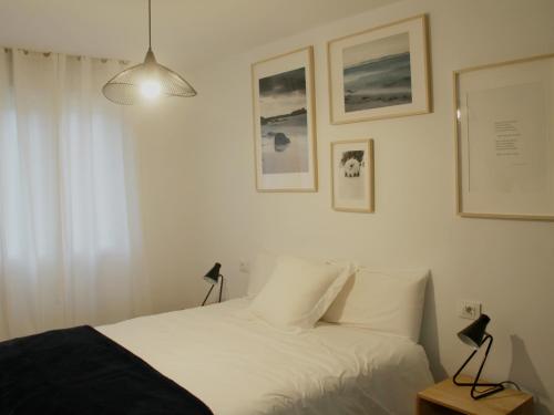 布埃乌Apartamento Lapamán的一间卧室配有一张铺有白色床单的床,墙上挂有图片
