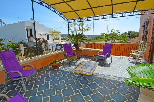 帕图Casa Spano 1 - RosariaVacanze的阳台的庭院配有紫色椅子