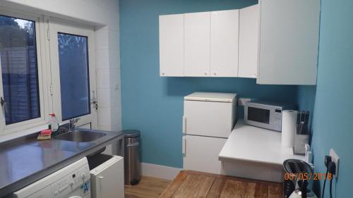 伦敦Hill Apartments的厨房配有白色橱柜和蓝色的墙壁