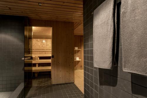 弗利姆斯T3 Alpenhotel Flims的浴室设有黑色瓷砖墙壁和木门。