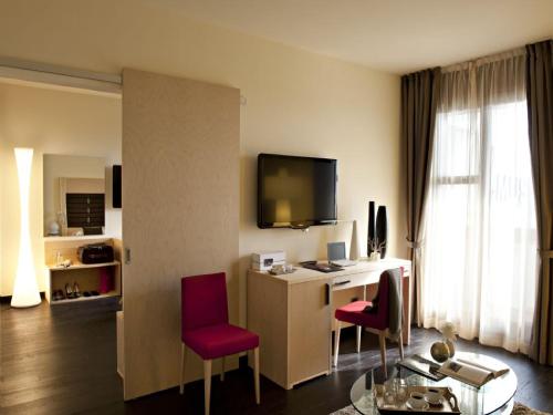 普拉托艺术博物馆酒店的酒店客房配有书桌和红色椅子
