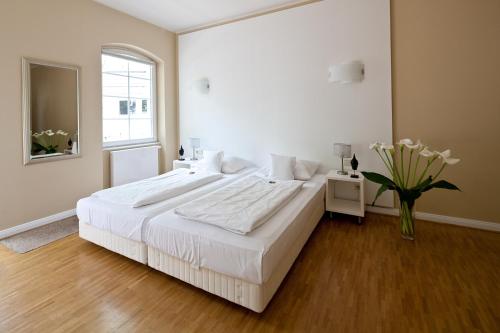 杜塞尔多夫施恩兰伯格酒店的白色的卧室设有一张大床和花瓶
