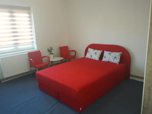 布尔奇科西斯特姆旅馆的一间卧室配有红色的床和两把椅子