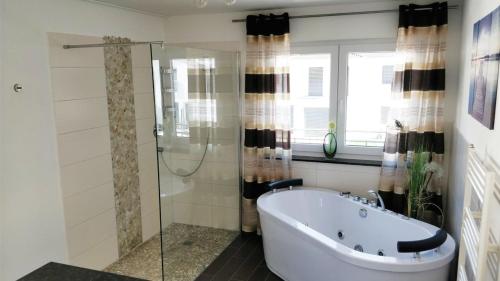 辛根FeWo - bei Tati 95qm的带浴缸和玻璃淋浴间的浴室。