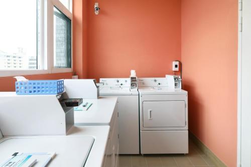 台中市MINI HOTELS (台中火车站馆)的洗衣房配有白色洗衣机和橙色墙壁