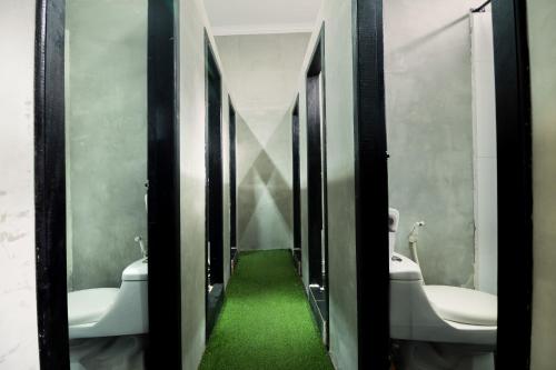 暹粒池畔派对旅舍的一间带两个卫生间的浴室,铺有绿色地板