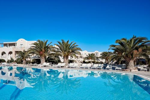 佩里沃罗圣米拉马雷海滩度假村的一座棕榈树和椅子的大型游泳池