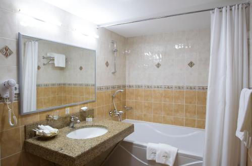 阿特劳阿特劳达斯坦酒店的一间带水槽、浴缸和镜子的浴室