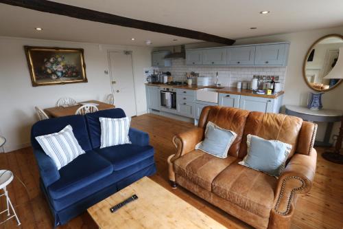 莱姆里吉斯Monmouth House Apartments, Lyme Regis Old Town, dog friendly, parking的客厅配有两把椅子和蓝色沙发