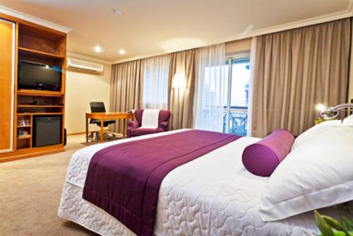 里约热内卢Bourbon Barra da Tijuca Residence的酒店客房配有一张带紫色枕头的大床