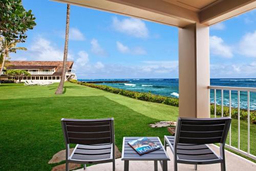 卡帕阿ISO酒店的俯瞰大海的门廊上设有两把椅子和一张桌子