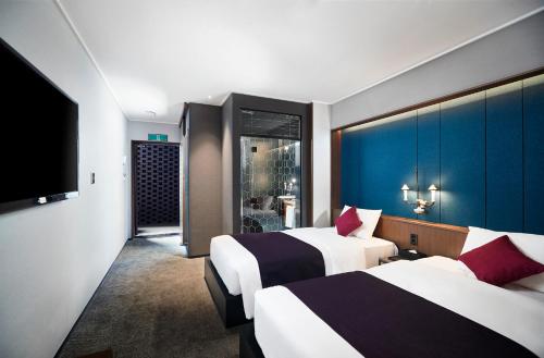 釜山South Vandeco Hotel的酒店客房设有两张床和一台平面电视。
