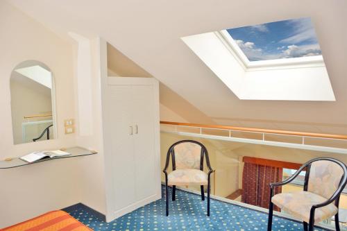梅纳焦梅娜吉欧大酒店的一间设有两把椅子和天窗的房间