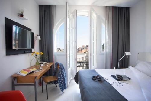 里昂学院酒店的配有一张床、一张书桌和一扇窗户的酒店客房