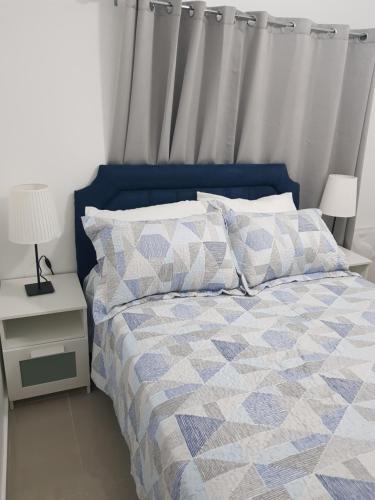 博卡奇卡KSL Residence的一张带蓝色和白色棉被和枕头的床