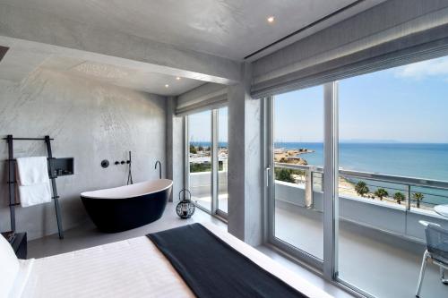 雅典Poseidon Athens Hotel的带浴缸的浴室,享有海景。