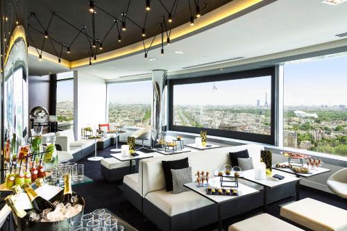 库尔布瓦巴黎狄芬思美利亚酒店的餐厅配有沙发、桌子和大窗户