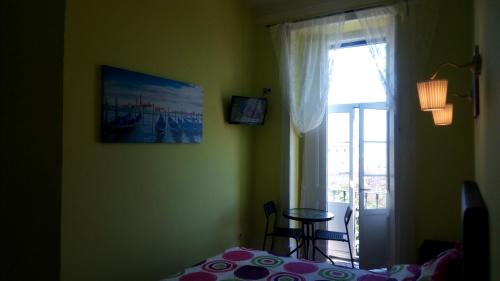 里斯本塞纳里奥卡迪塔旅舍的一间卧室设有一张床、一个窗口和一张桌子