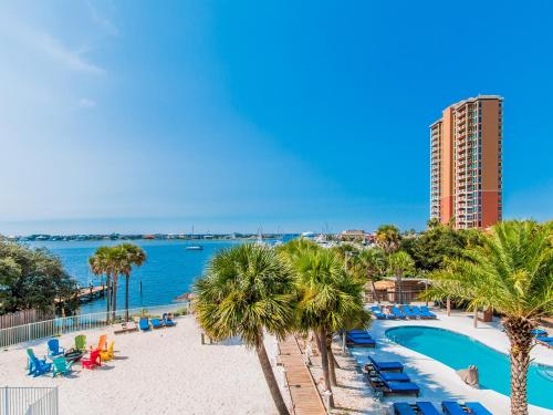 彭萨科拉海滩冲浪和沙滩酒店的一座带游泳池、棕榈树和大楼的度假村