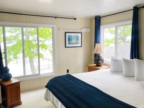 Hubbard LakeChurchill Pointe Inn的一间卧室设有一张大床和两个窗户。