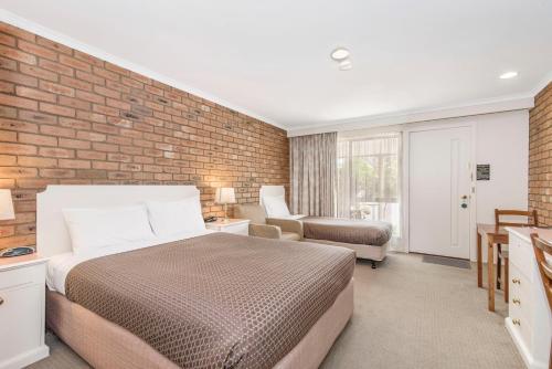本迪戈黄金广场汽车旅馆的一间卧室设有一张床和砖墙
