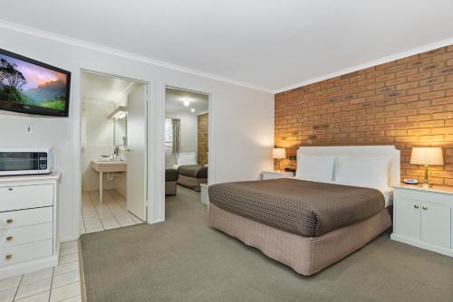 本迪戈黄金广场汽车旅馆的一间卧室设有一张床和砖墙